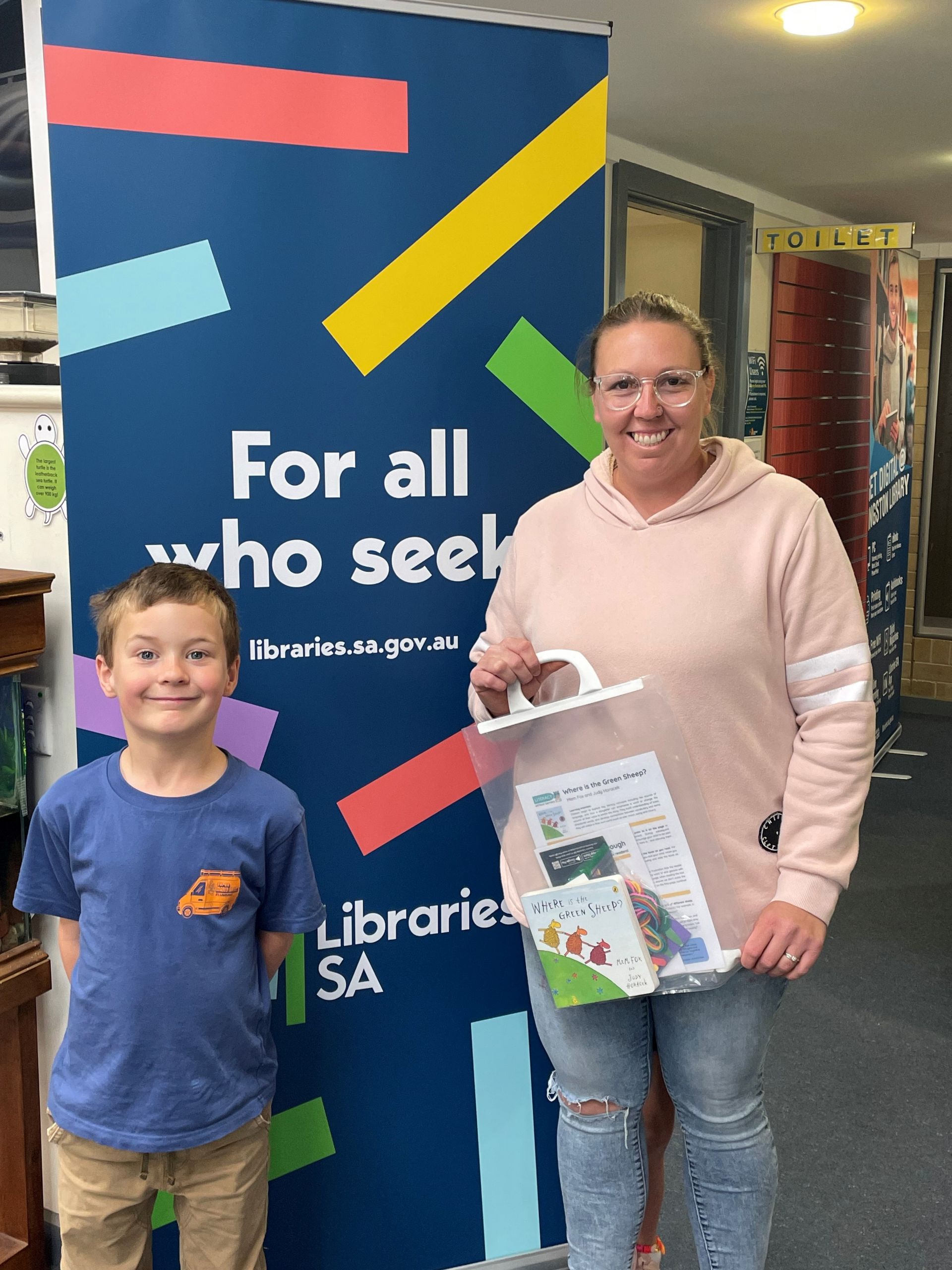Kingston Library Mum and son standing in front of Library sign