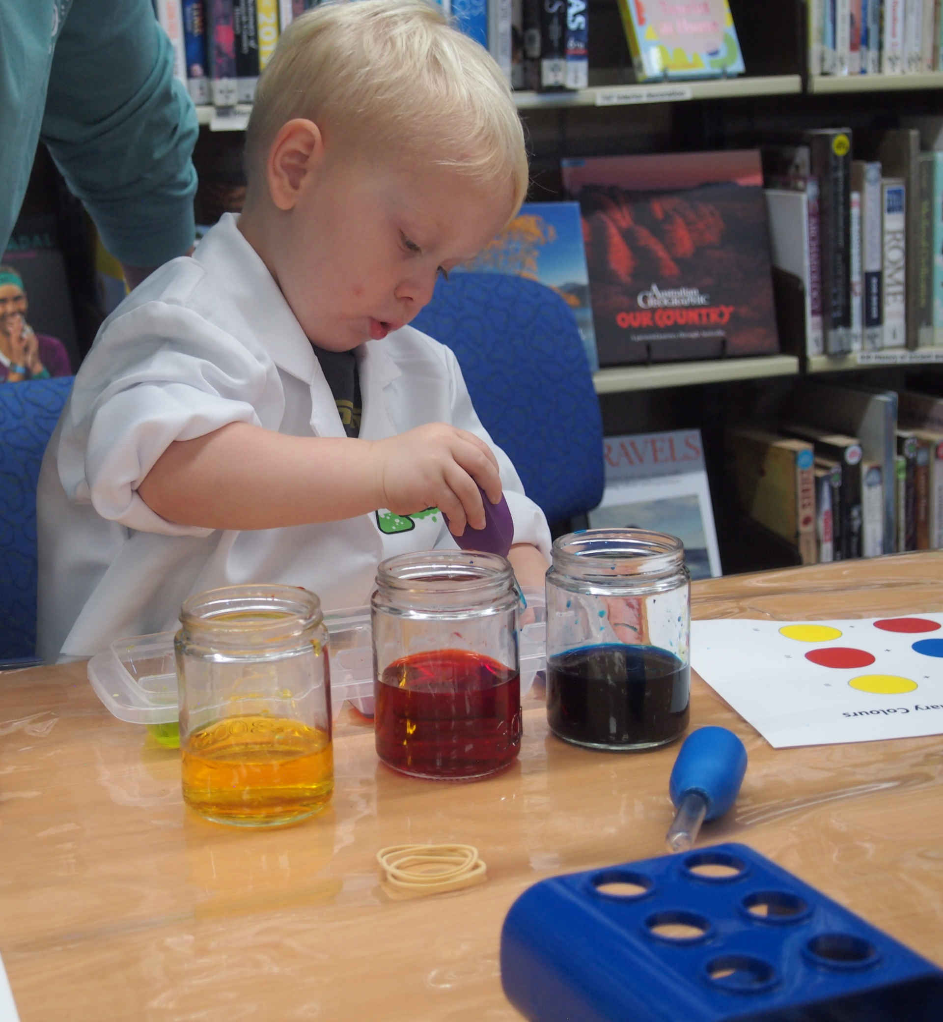 A boy mixing coloured liquids with a bulb syringe