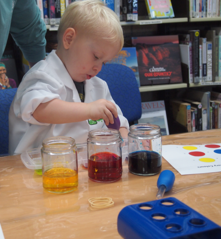 A boy mixing coloured liquids with a bulb syringe
