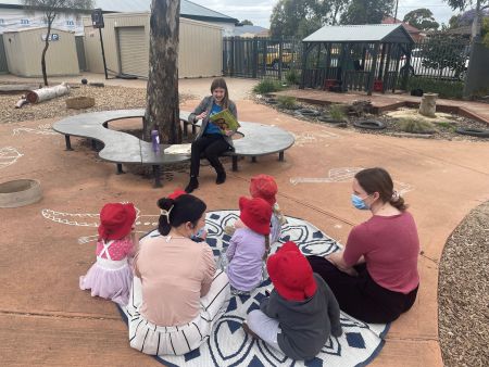 Children on a mat outside listening to a story