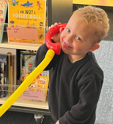 A boy using a talking tube (telephone) at the library.