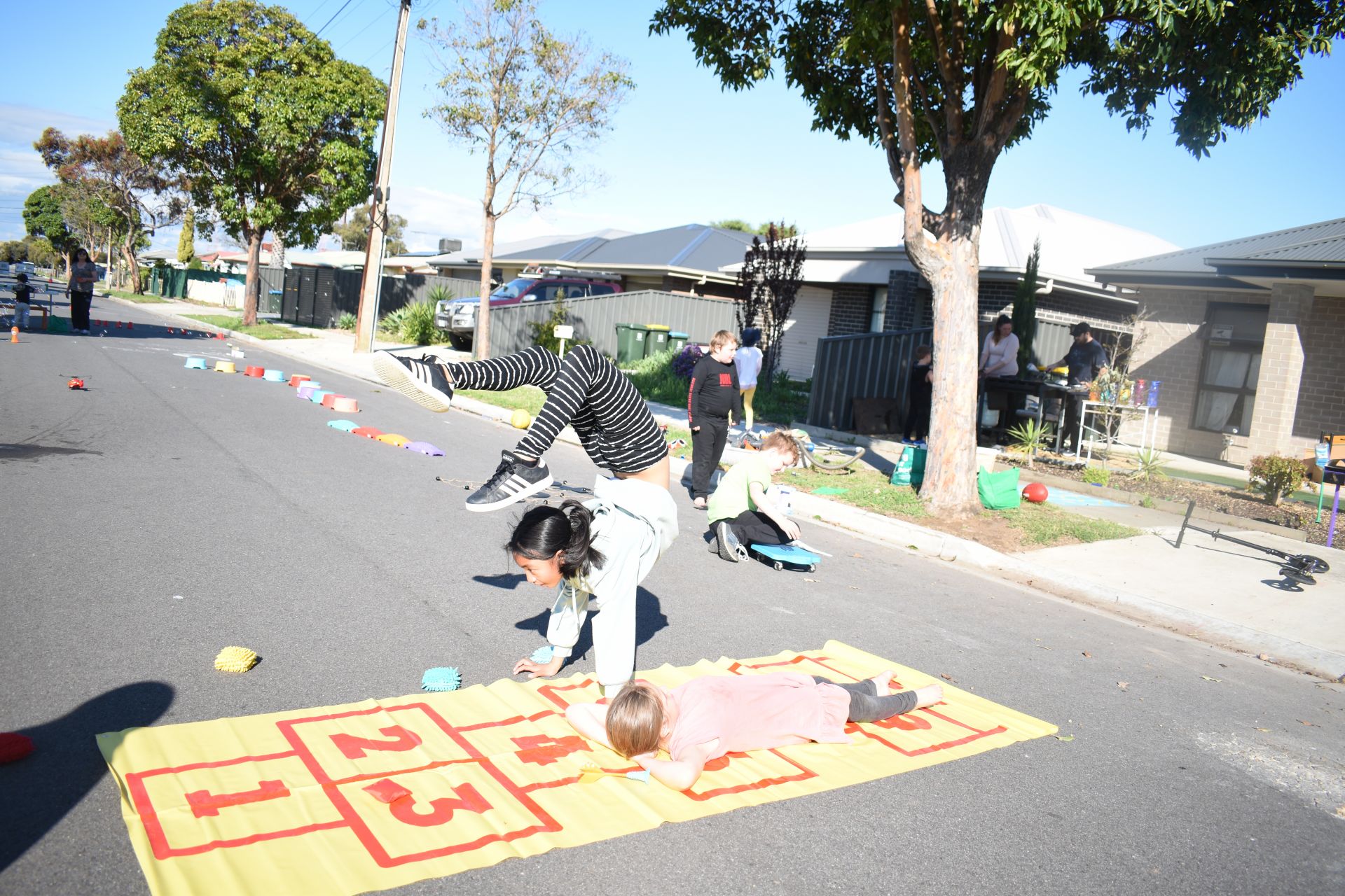 Children playing on a hopscotch mat on the street