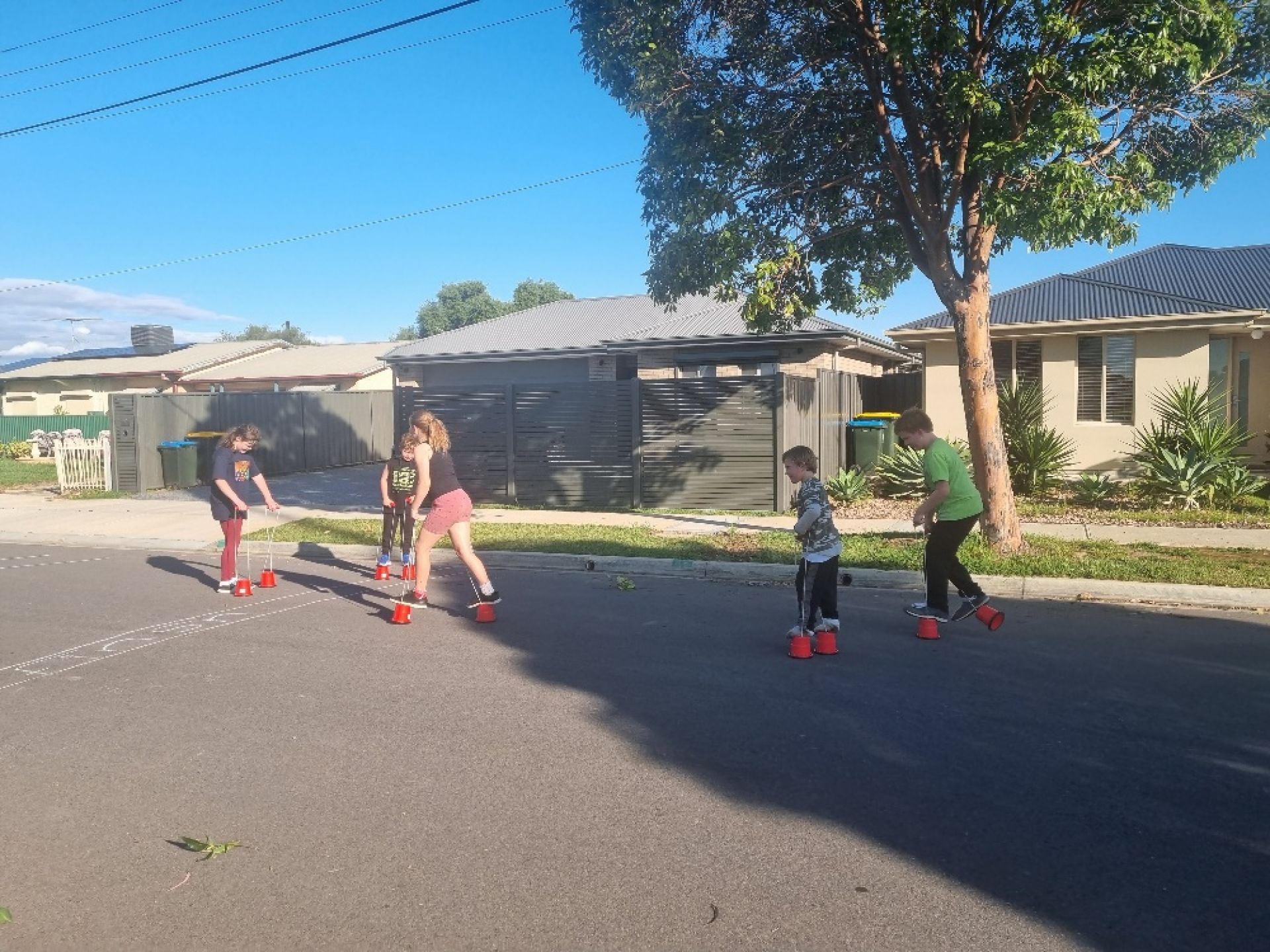 Children walking on bucket stilts on the street
