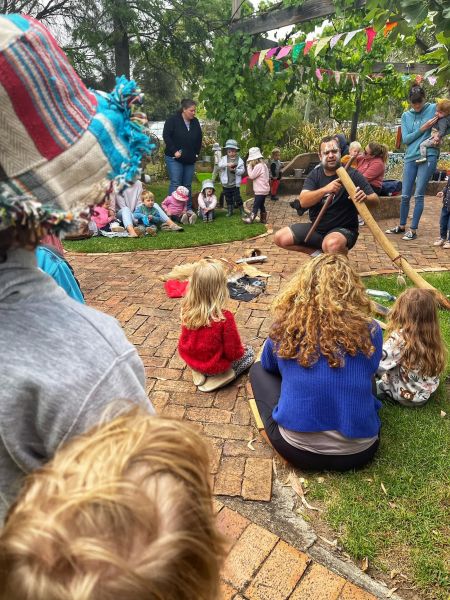 A group of children sitting and watching a indigenous performance.
