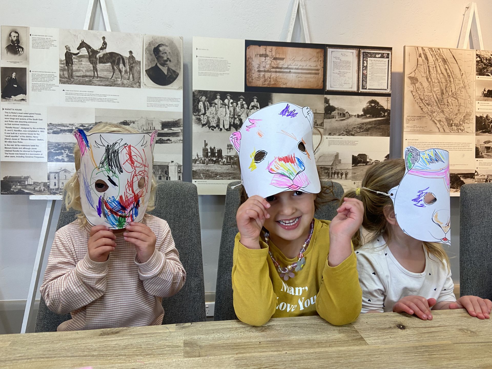 3 children wearing the masks they have coloured in.