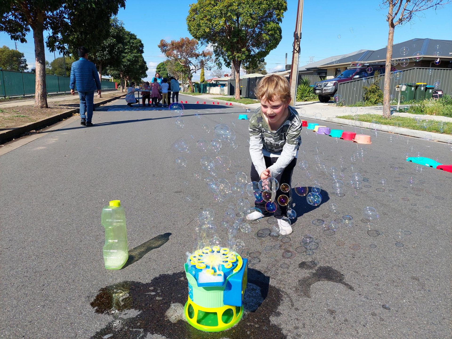 A boy with a bubble machine on the street