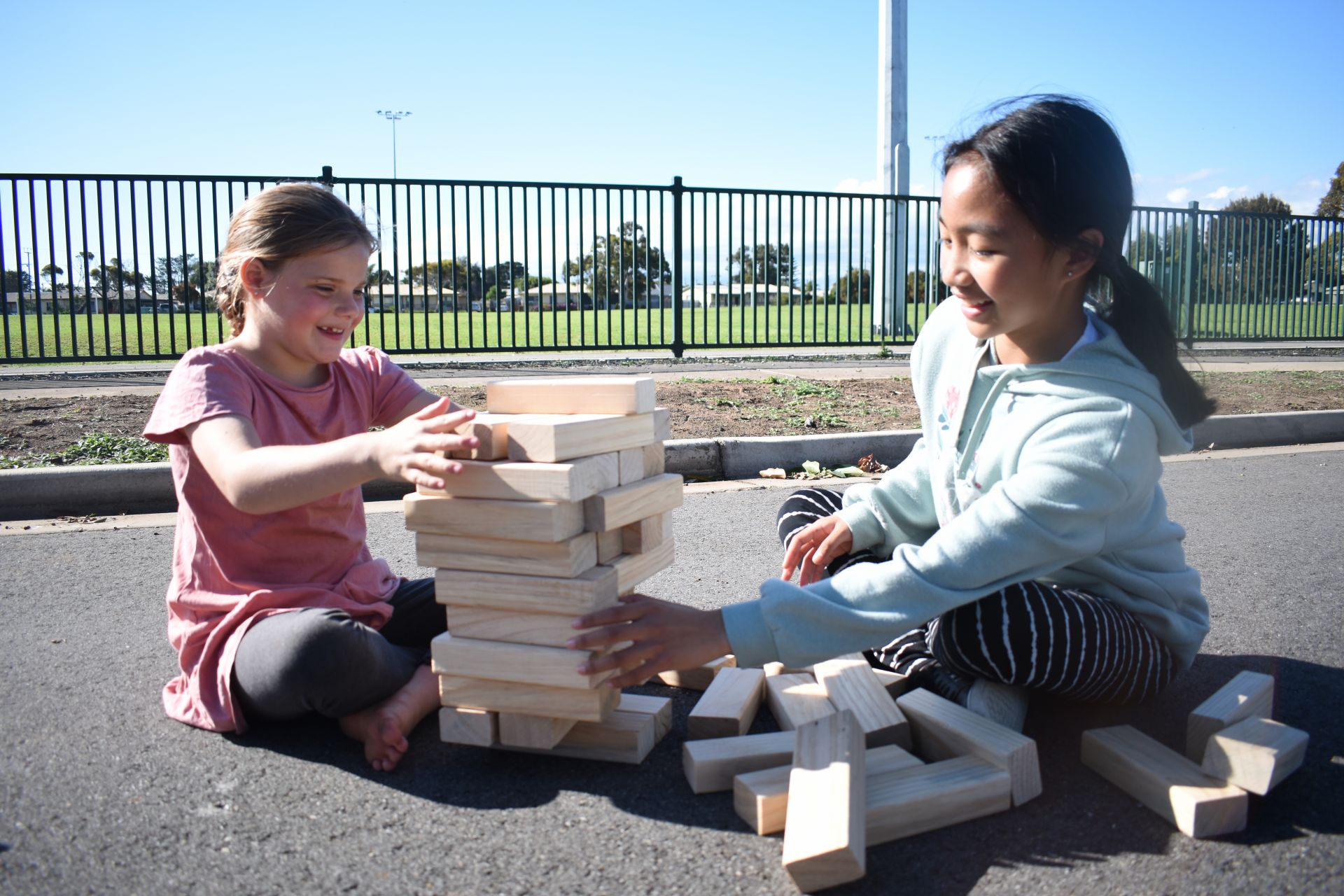Two children playing with wooden blocks on the street