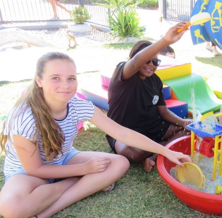 Two young girls playing with a sand table
