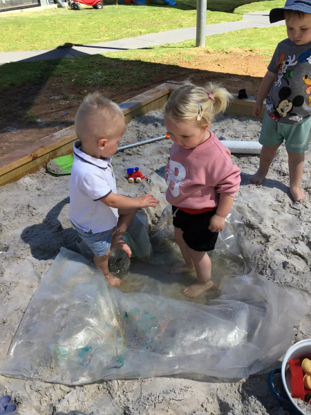 Two children playing together in the sand pit